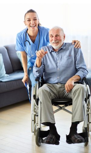 Doctor or nurse caregiver with senior man ina wheelchair at home or nursing home